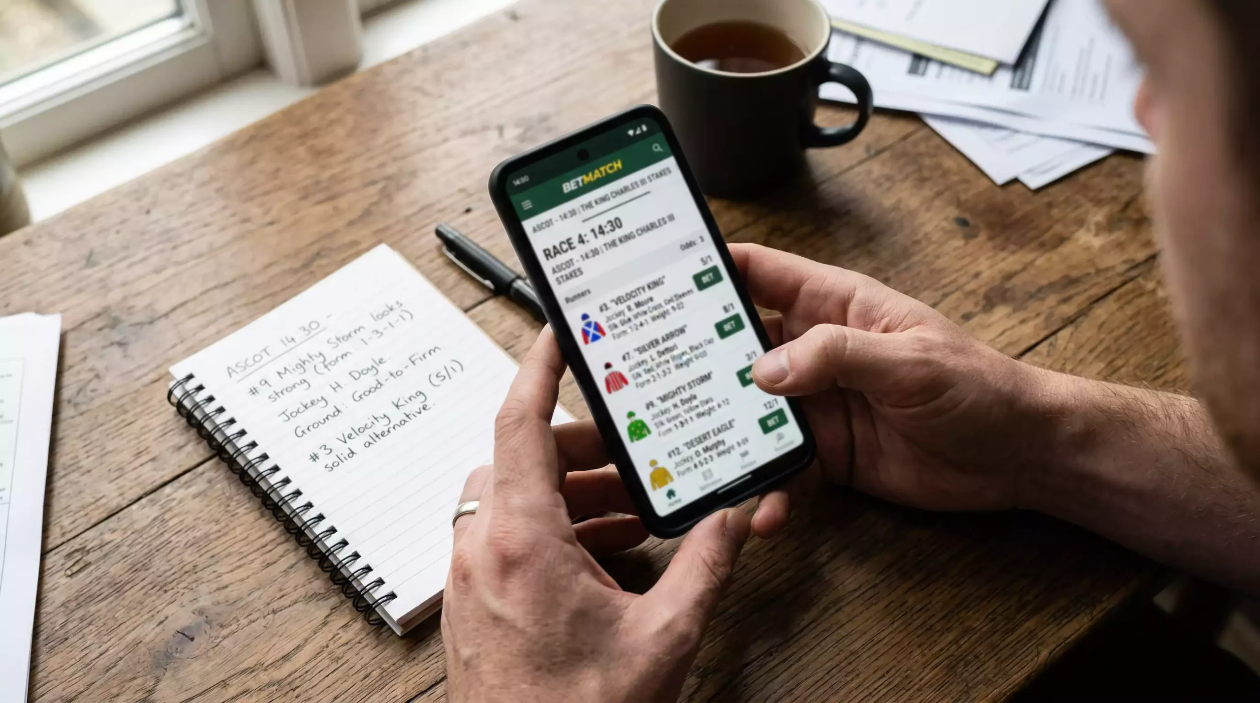 Hands holding smartphone with horse racing betting app showing race card and odds